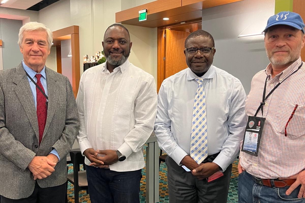 David Light and Emilio Paris of ISP with Rodney Sikumba and Dr. Chibamba Kanyama of Zambia, standing together in a room at a convention center.
