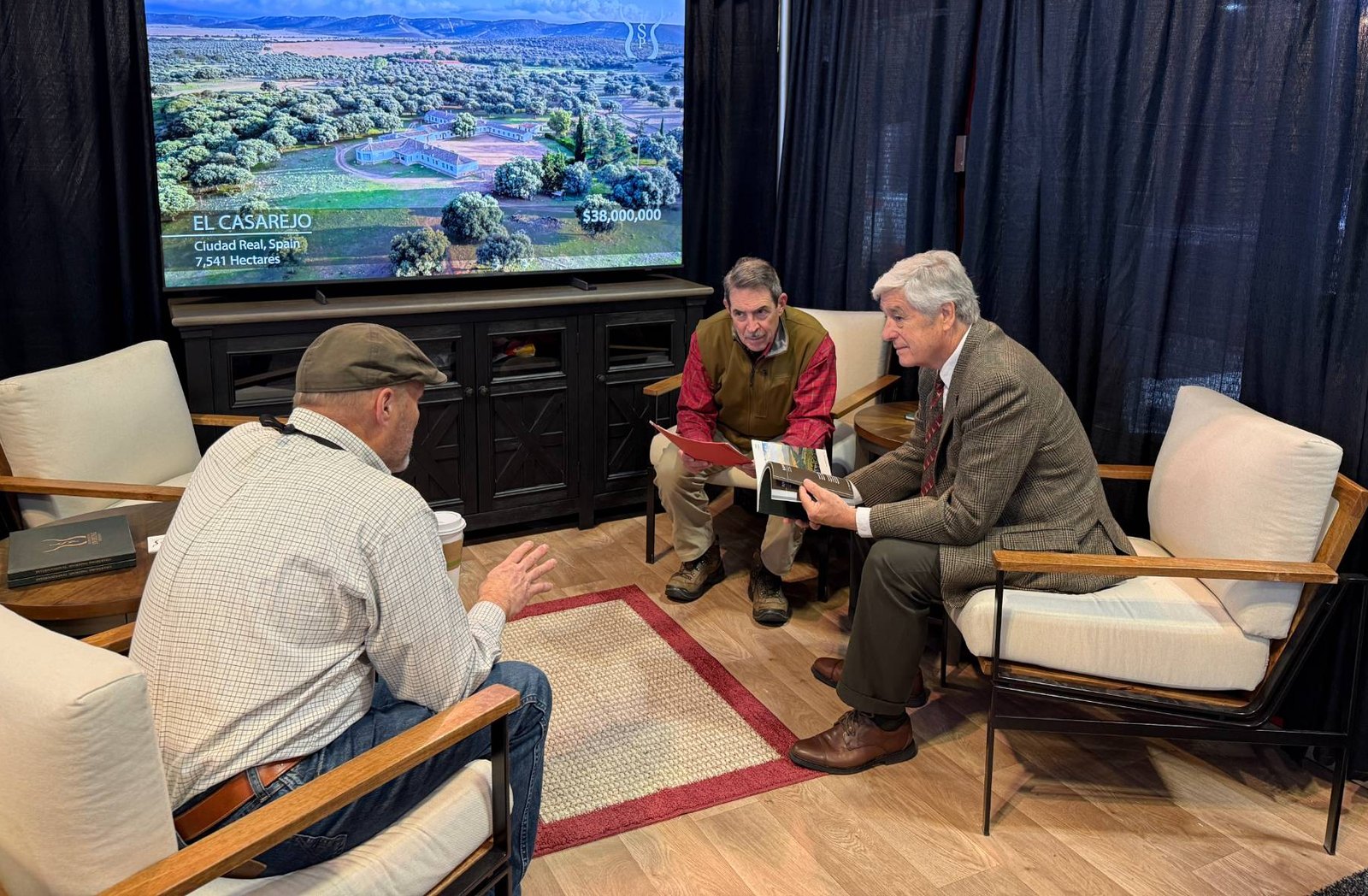 A buyer meeting at the ISP stand in Nashville, a book held open, El Casarejo on the screen behind